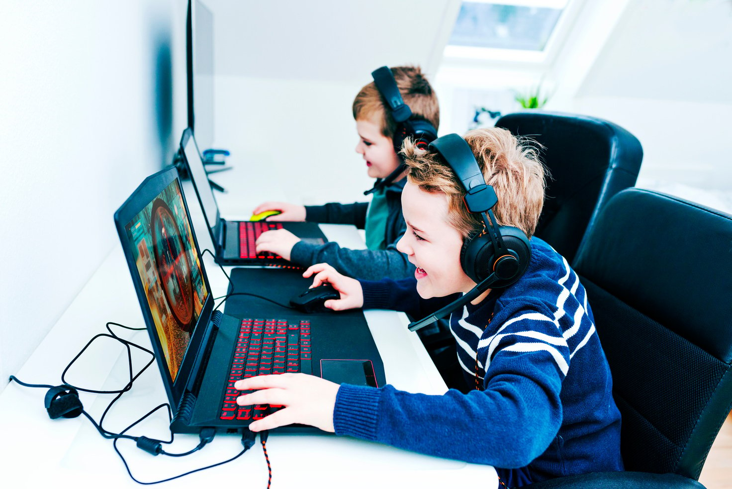 Happy boys have fun playing video games on gaming laptops